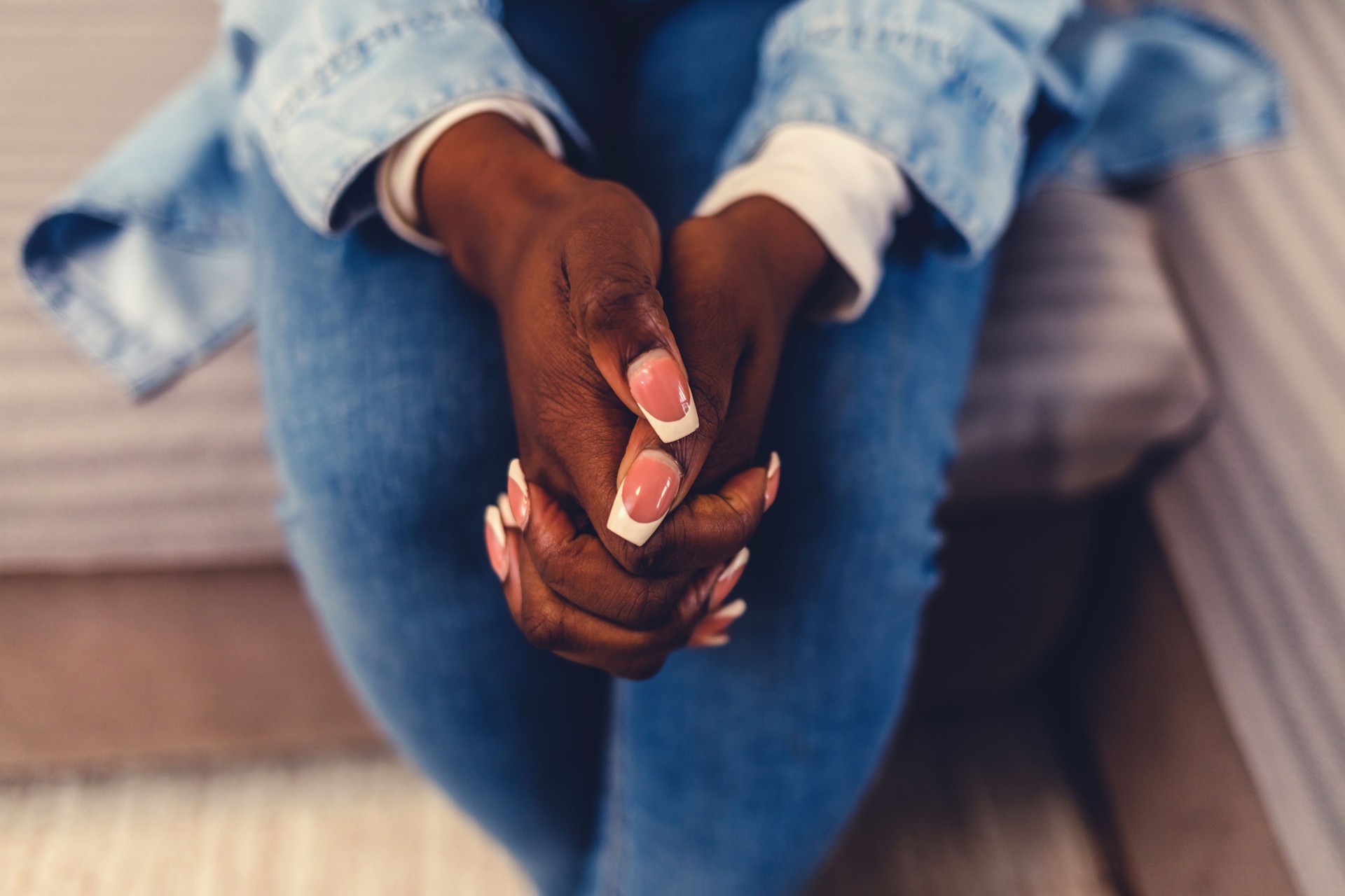 Cropped shot of an unrecognisable woman sitting alone and feeling anxious during her consultation. Closeup hands of anxious patient in therapy. Zoom in on hands of nervous person. Hands clasped, depressed person in psychotherapy.